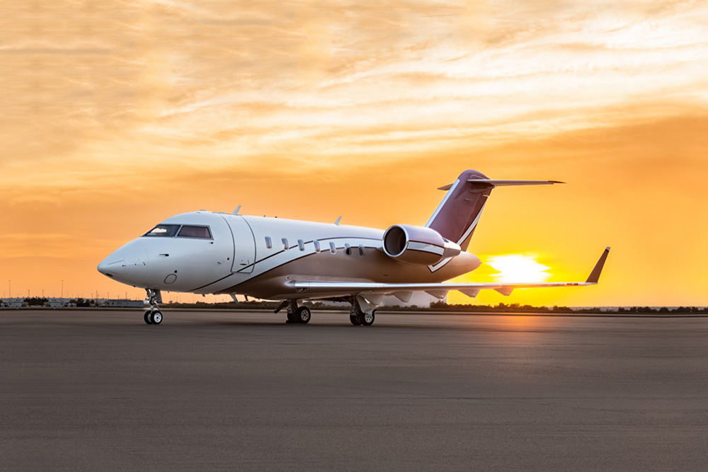 Challenger 605 private jet parked on the tarmac at sunset