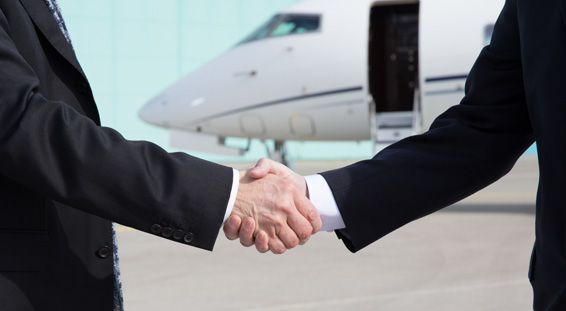 Two business men shaking hands in front of a private jet
